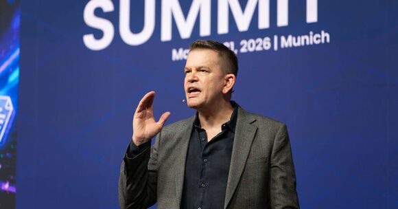 Speaker passionately presenting at a summit event in Munich, 2026.