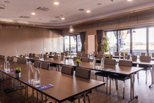 Moderne Konferenzraumausstattung mit Tischen, Stühlen und Wasserflaschen.