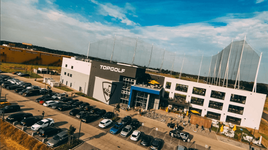 Luftaufnahme der Topgolf-Anlage mit Parkplatz und Menschen draußen.