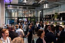 A bustling networking event with people mingling and talking in a modern space filled with plants.