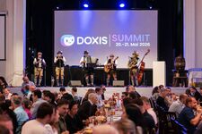 Musicians in traditional attire perform at Doxis Summit event with attendees dining.