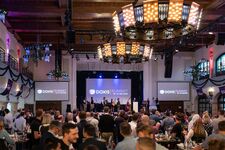 Crowd at the Doxis Summit event, with a stage and musicians performing.