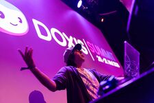 A speaker gestures enthusiastically on stage at Doxx Summit event.