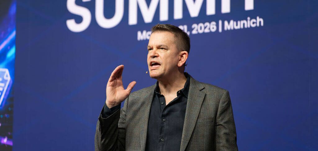 Speaker passionately presenting at a summit event in Munich, 2026.