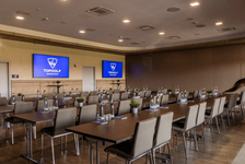 Konferenzraum mit Tischen, Stühlen und Topgolf-Branding auf Bildschirmen.